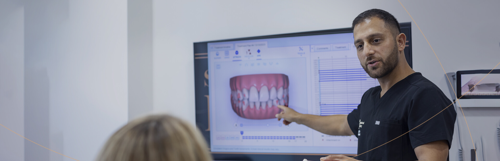 Image of a dentist explaining a digital model of a patient's teeth on a screen during a consultation.