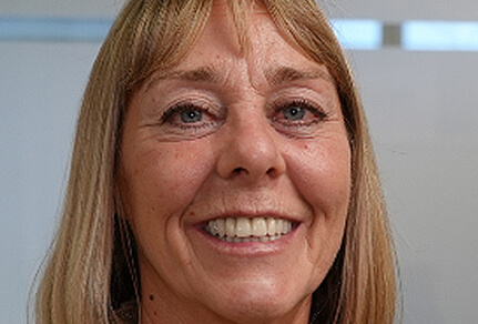 A close-up image of a woman smiling, showcasing her bright teeth after receiving dental implants.