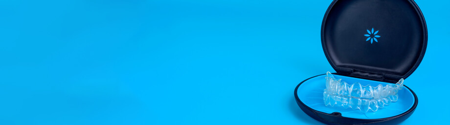 An Invisalign aligner inside a black carrying case with a blue background.
