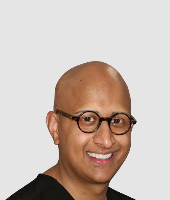 Portrait of a smiling dentist wearing glasses and a black dental scrub.