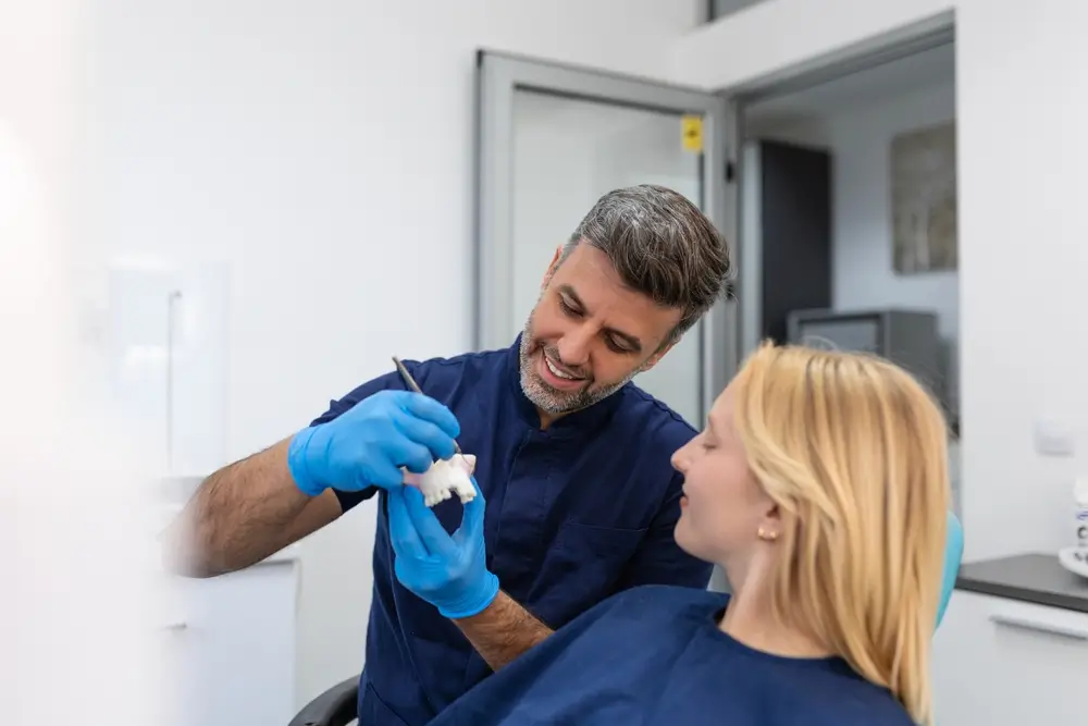 Dentist showing dental mold to a female patient.