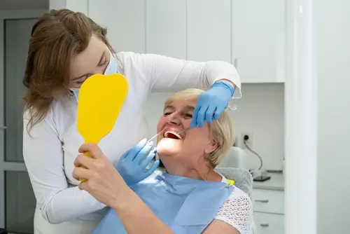 Image of a dental professional showing a patient their new dental implants using a mirror during a consultation.